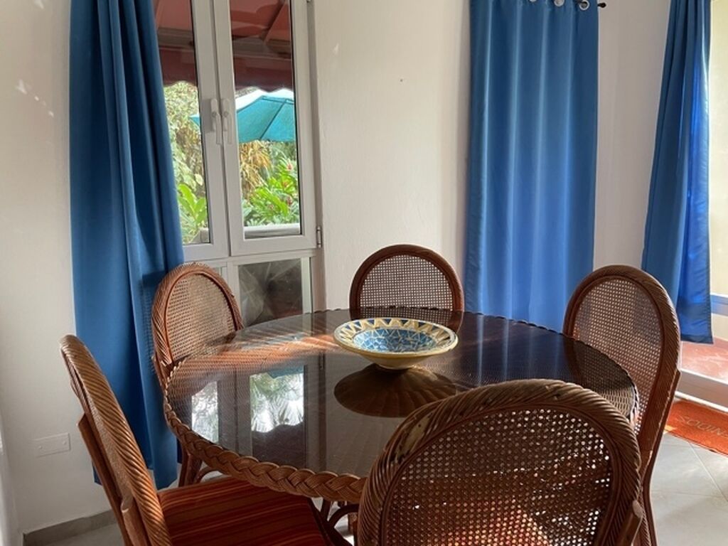 A round glass table with a blue and white patterned bowl, surrounded by wicker chairs.