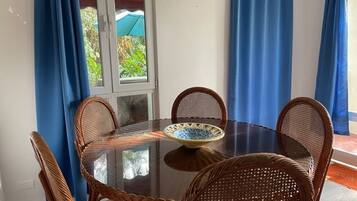 A round glass table with a blue and white patterned bowl, surrounded by wicker chairs.