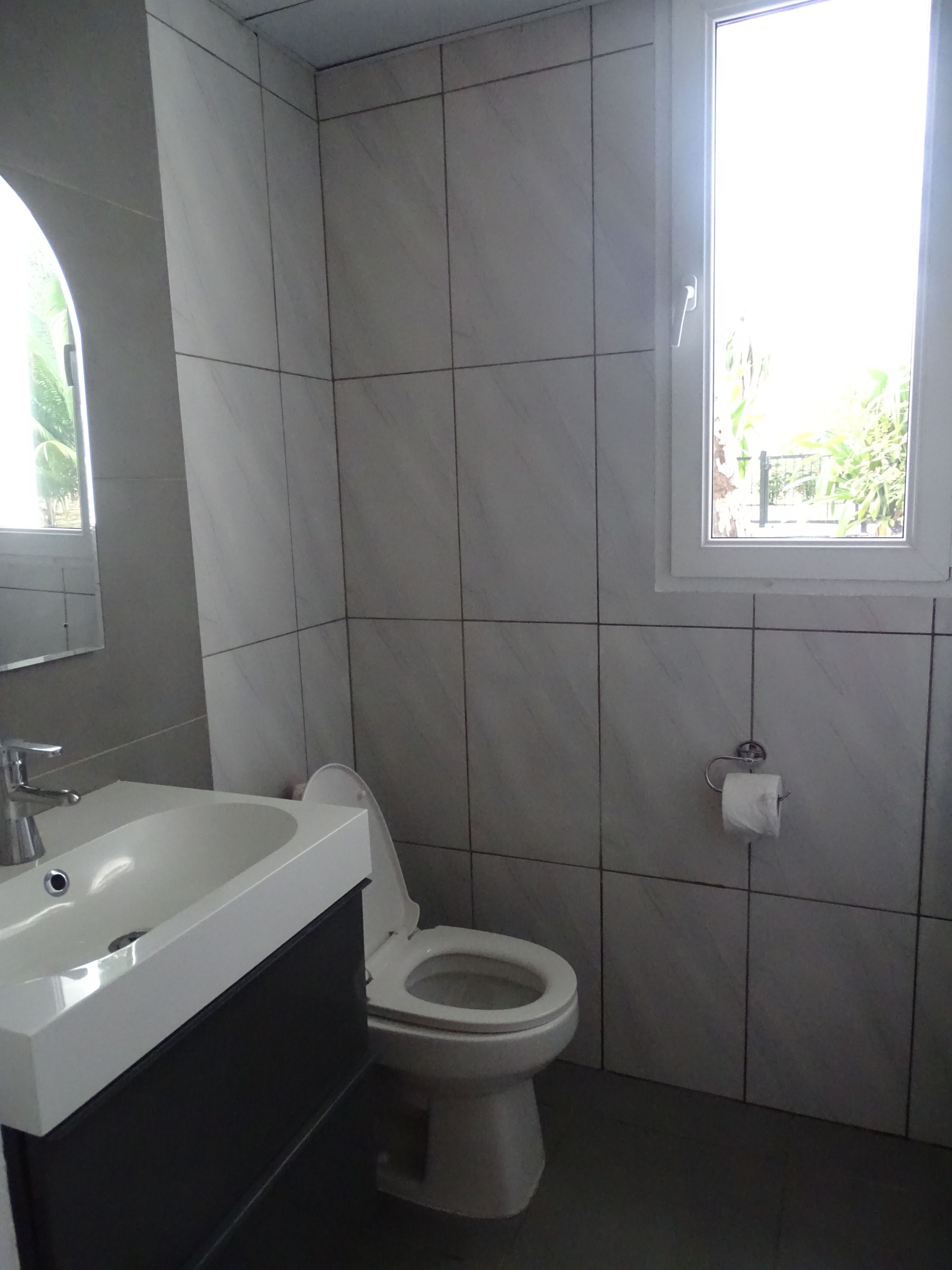 Ein Badezimmer mit einem weißen Waschbecken, einer Toilette und einem Fenster.