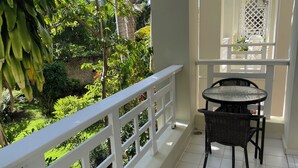 A balcony with a white railing, a round table, and two chairs. - Albatros (Cabarete)