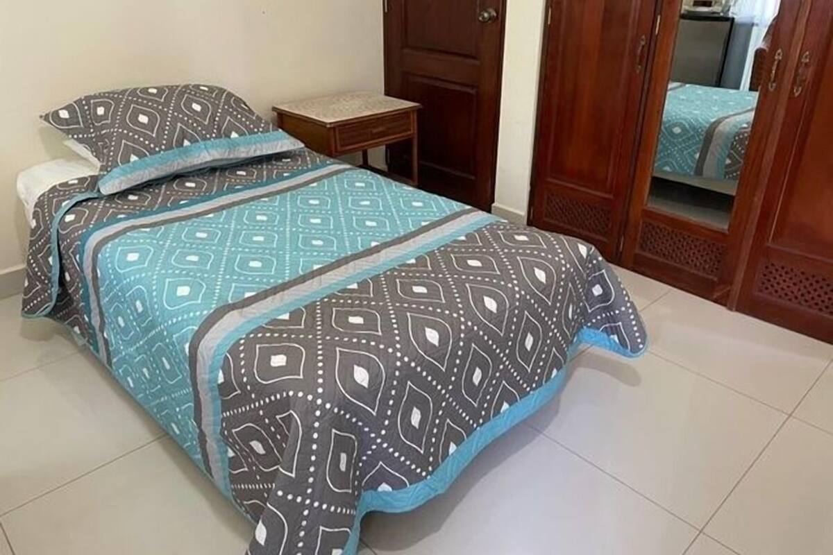 Ein Schlafzimmer mit zwei Betten, einem Holzschrank und einem kleinen Nachttisch.