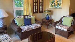 A living room with wicker furniture, a glass coffee table, and a painting on the wall. - Albatros (Cabarete)