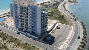 Un hotel de gran altura con varios pisos, una piscina en la azotea y un estacionamiento.