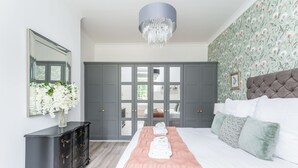 A bedroom with a large bed, a dresser, a mirror, and a chandelier. - 3 Feversham House · Spacious 1-Bed Apartment in the Heart of York- Pass the Keys (York)