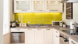 A modern kitchen with white cabinets, a yellow backsplash, and a stainless steel range hood. - 3 Feversham House · Spacious 1-Bed Apartment in the Heart of York- Pass the Keys (York)