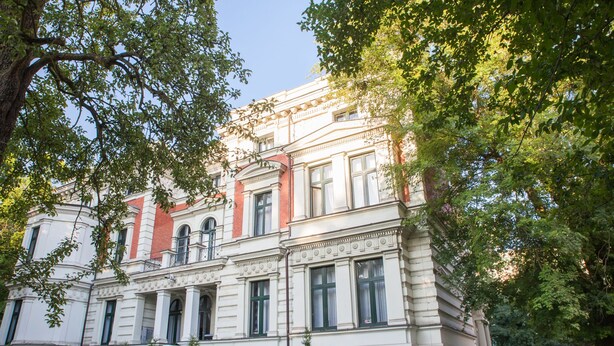 Un edificio clásico con arquitectura simétrica, amplias ventanas y una entrada central.