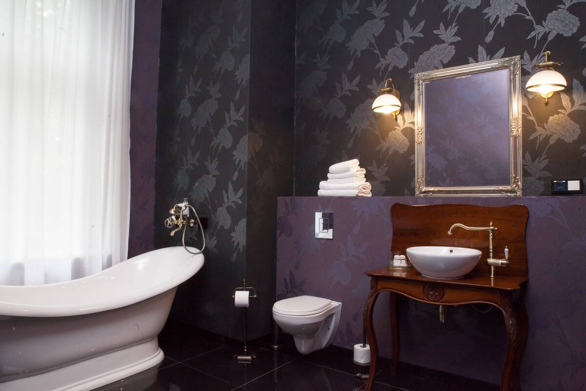 A bathroom with a freestanding bathtub, a toilet, a sink with a mirror, and a towel rack.
