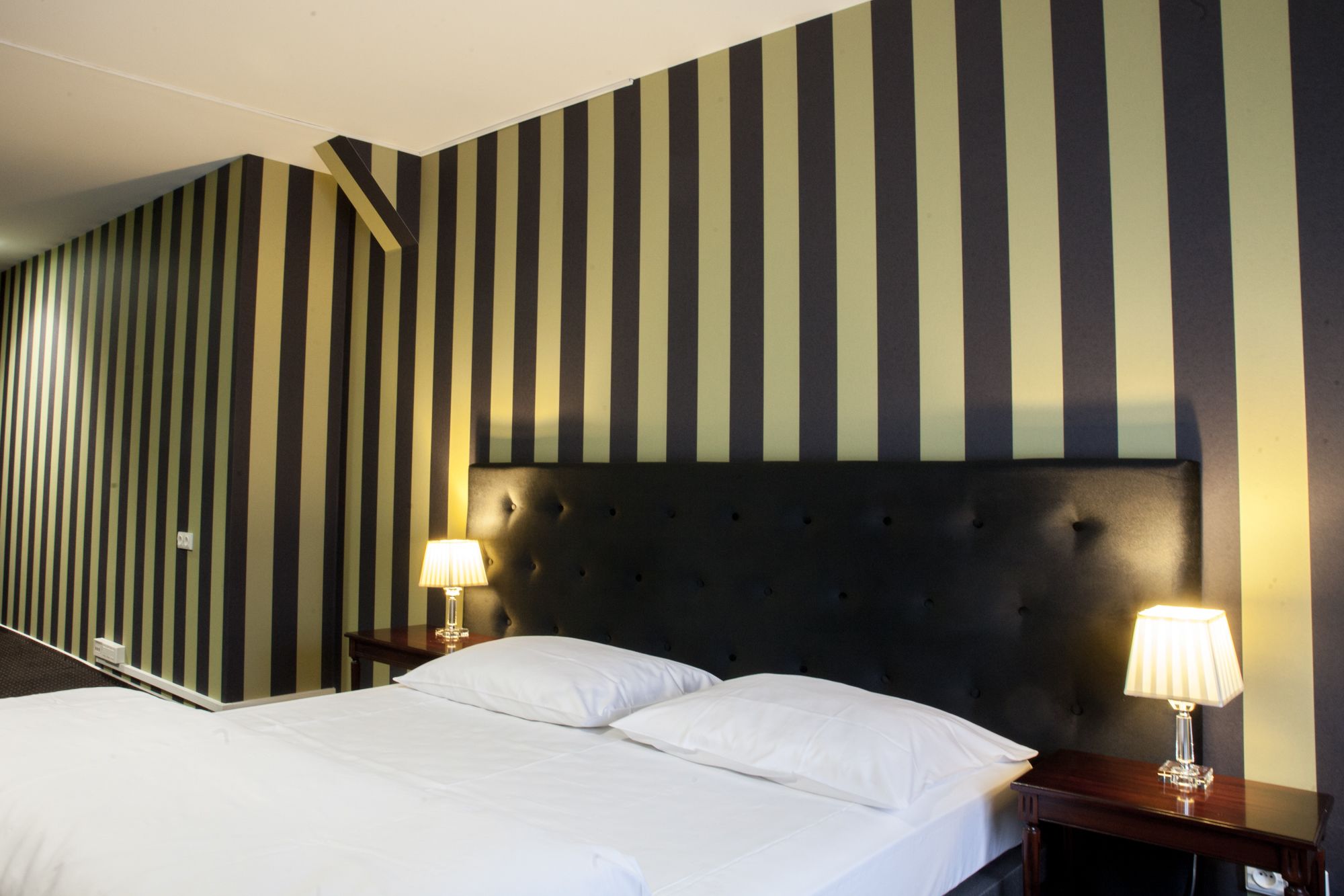 Ein Hotelzimmer mit einem Bett, zwei Nachttischen und einer gestreiften Wand.