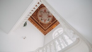 Una escalera blanca con techo decorativo que presenta un diseño floral y un panel de madera.