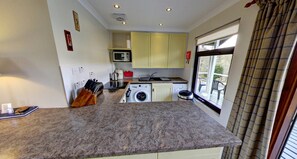 A compact kitchen with a washing machine, a microwave, and a sink. - Beautiful 4 star 2 bedroom chalet with stunning loch and mountain views (Crianlarich)