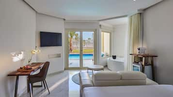 A hotel room with a bed, a desk with a chair, a TV mounted on the wall, a small table with a lamp, and a view of a pool through a glass door.