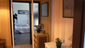A hotel room with a bed, a bedside table with a lamp and flowers, a mirror, and a framed picture on the wall. - GRAND STUDIO sea view, 47M2 tastefully decorated, 3 stars (Dinard)