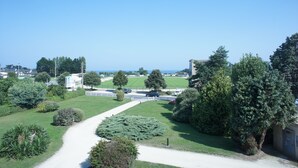 A landscaped area with a pathway, trees, and a distant view of the sea. - GRAND STUDIO sea view, 47M2 tastefully decorated, 3 stars (Dinard)