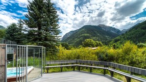 A wooden deck with a glass enclosure and hot tub, overlooking a mountainous landscape. - Deluxe Unit with Unbeatable Deck Views (Telluride)
