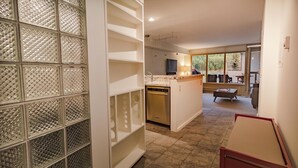 A modern kitchen with a central island, a dining area with a table and chairs, and a view of the outdoors through large windows. - Deluxe Unit with Unbeatable Deck Views (Telluride)
