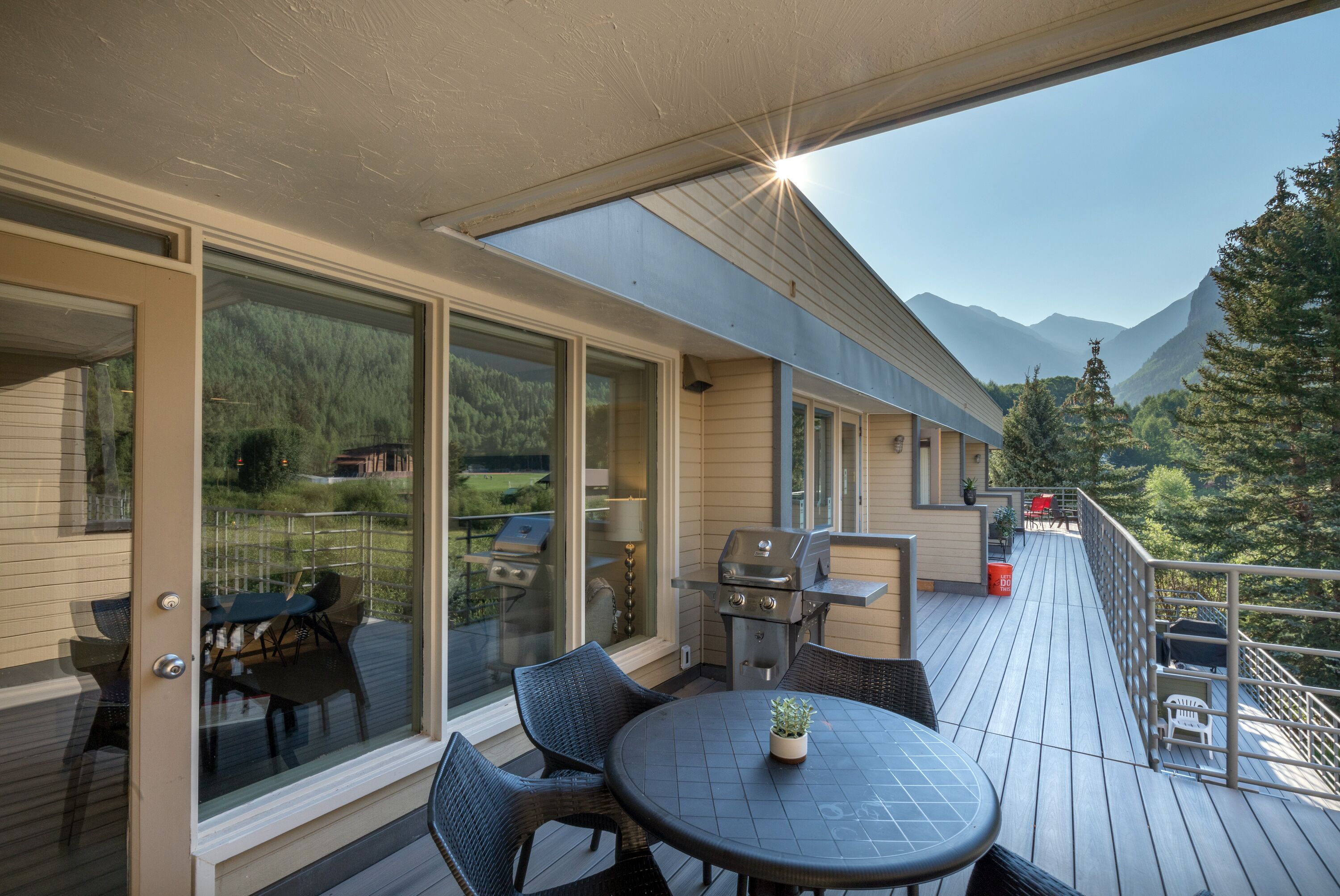 Eine Terrasse mit Grill, Esstisch und Stühlen, mit Blick auf eine Berglandschaft.