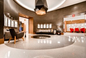 A modern lobby with a circular seating area, a reception desk, and a wall with framed pictures. - Bluebird Suites near Pentagon (Arlington)