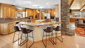 A spacious kitchen with wooden cabinets, a central island with bar stools, and a stone accent wall.