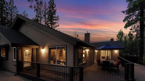 A wooden cabin with a deck, large windows, and a covered outdoor seating area.