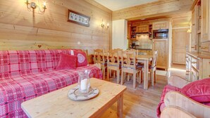 Ein gemütliches Holzambiente mit einem roten Karo-Sofa, einem Holzesstisch und einer Küchenzeile.