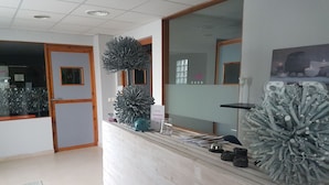 A reception desk with a mirror, a decorative plant, and a sign. - Hotel Almedina Spa (Medina-Sidonia)