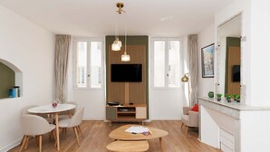 A modern living room with a TV, wooden entertainment unit, round dining table, and a fireplace. - Napoleon-2070-2 minutes walk from the Palais! (Cannes)