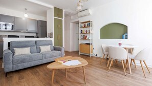 A modern living room with a grey sofa, wooden coffee table, and a dining area with a round table and chairs. - Napoleon-2070-2 minutes walk from the Palais! (Cannes)