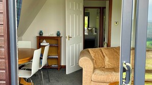 A cozy living room with a sofa, a dining table with chairs, and a bookshelf. - Glen Lodges (Rogart)