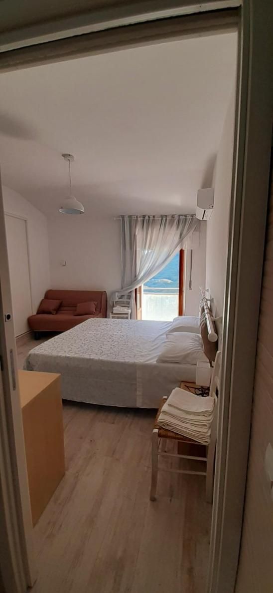Un dormitorio con una cama, una silla, un escritorio y un ventanal con cortinas.