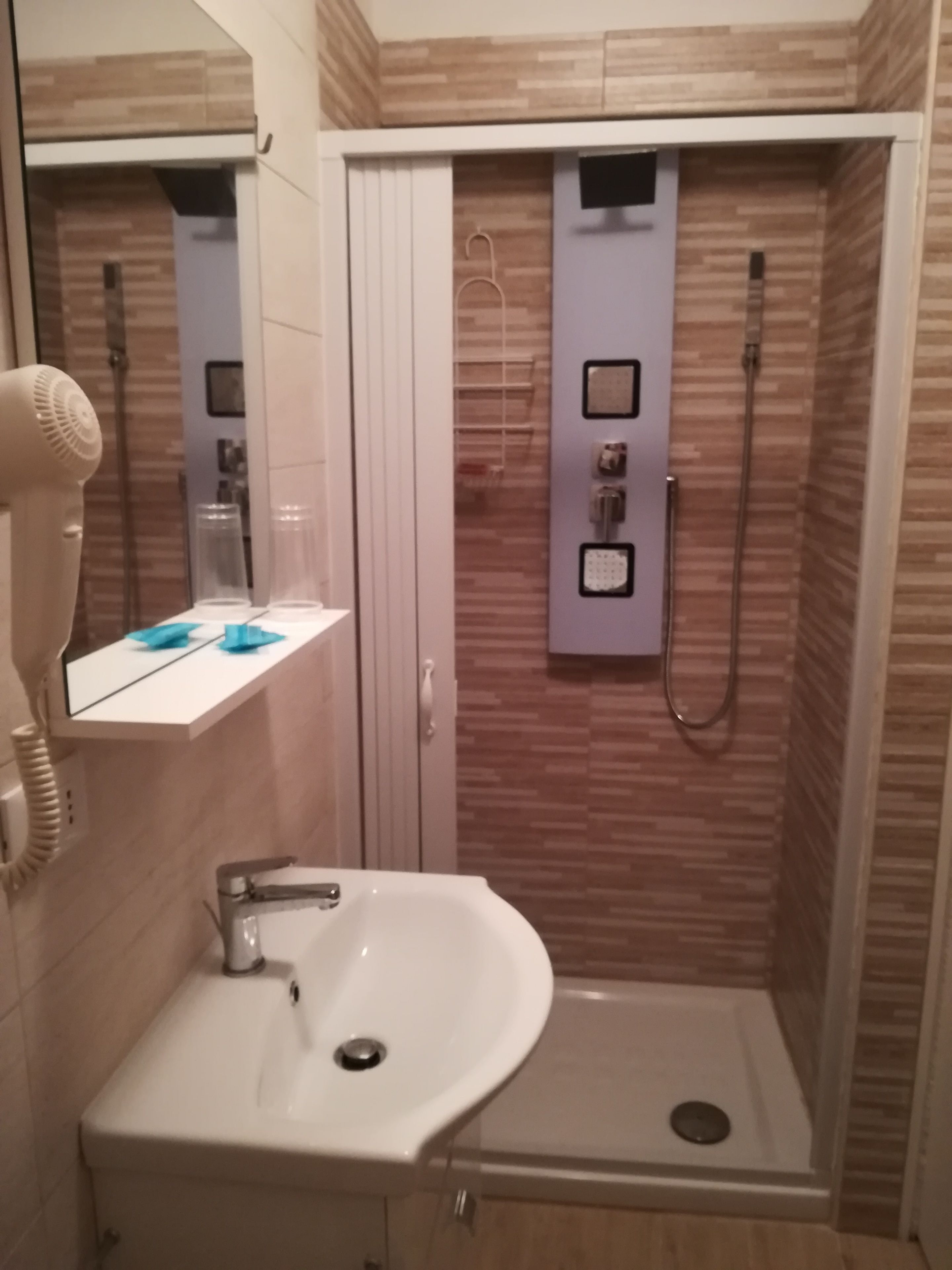 Un baño con ducha, lavamanos y secador de pelo.