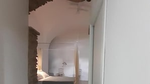 Un pasillo estrecho que conduce a un dormitorio con cama y una silla.