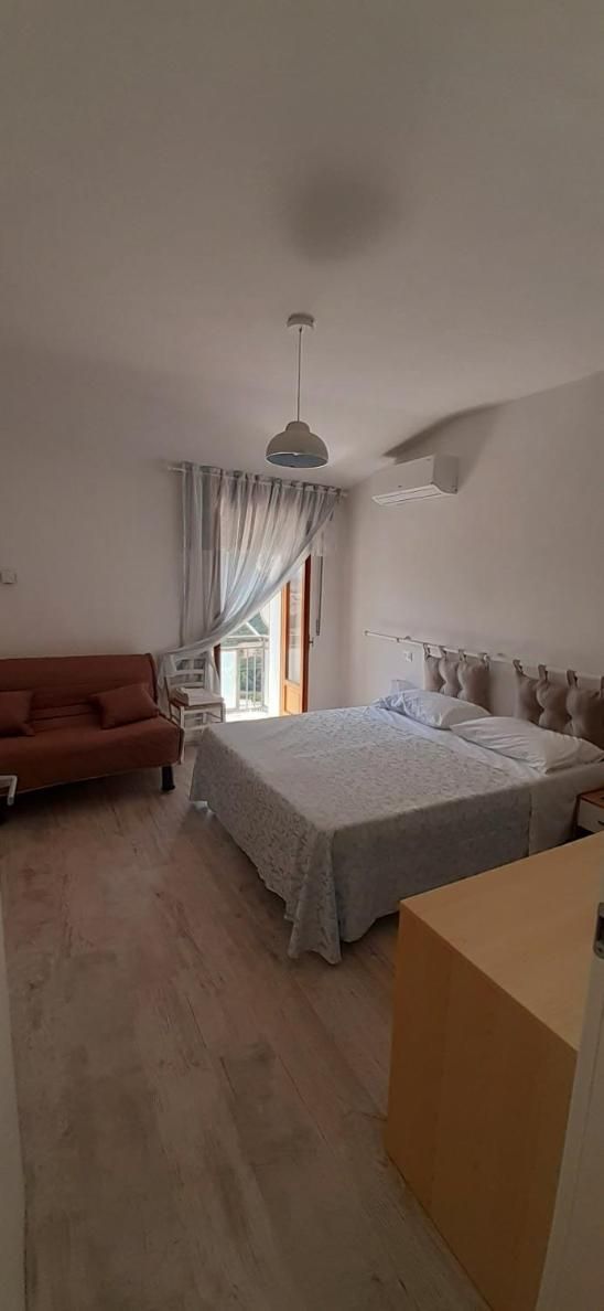 A bedroom with a bed, a sofa, a desk, and a window with curtains.