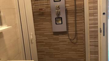 A shower with a control panel, a handheld showerhead, and a wall-mounted towel rack.
