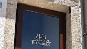 Puerta de madera con un panel de vidrio que muestra el logotipo "A&B BELVEDERE" y un candelabro.