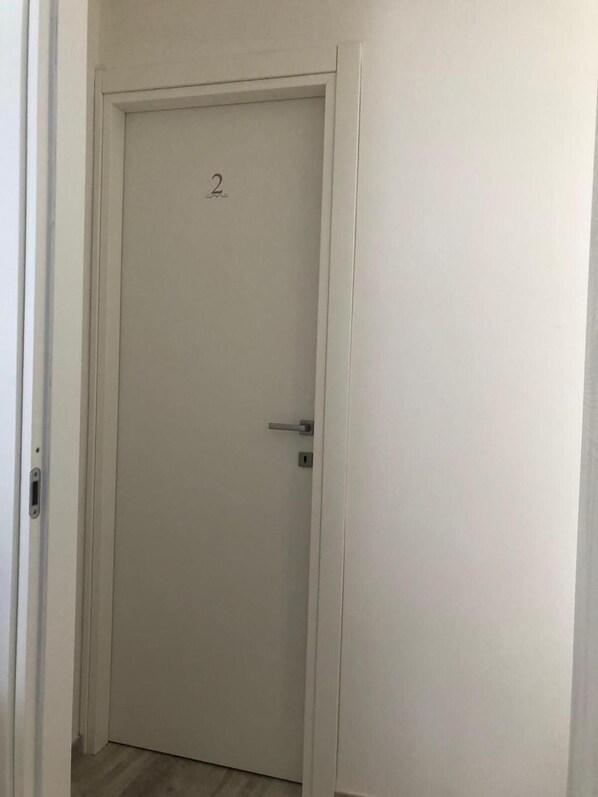 A closed white door with a number '2' above it, a door handle, and a keyhole.