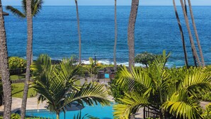 A pool area with palm trees and a view of the ocean. - LAST MINUTE DISCOUNT SPECIALS! End Unit. Direct Ocean View. Wrap-Around Lanai. (Kailua-Kona)
