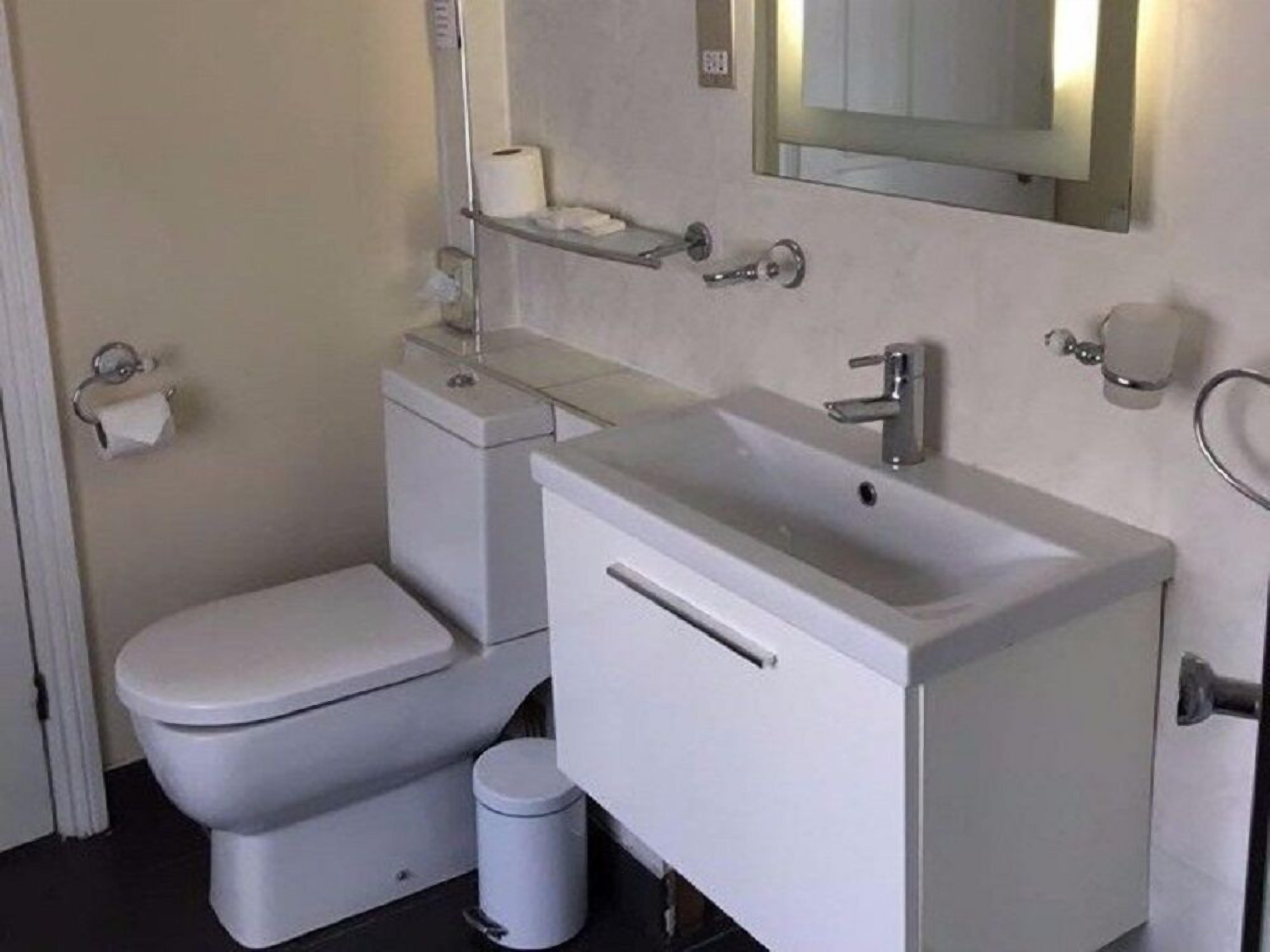 Un baño pequeño y moderno con inodoro, lavamanos y espejo.