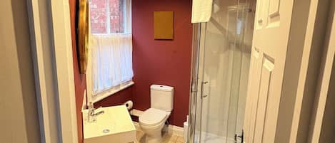 Une salle de bain avec des toilettes, un lavabo et une douche.