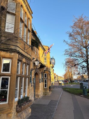 A historic building with multiple windows, a flag, and a street view.