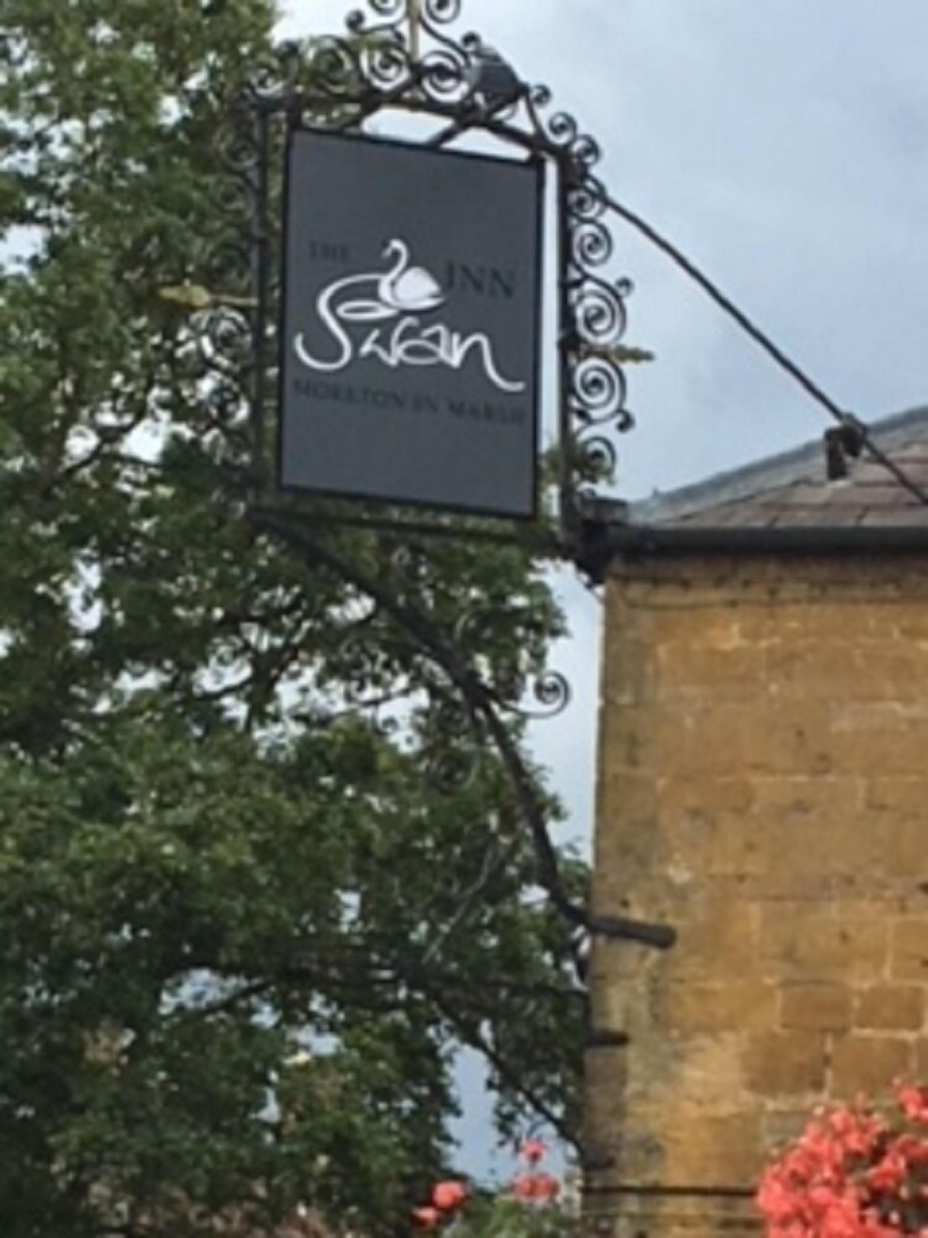 A sign for 'The Swan Inn' with a swan logo and the text 'Gourmet by Marie'.