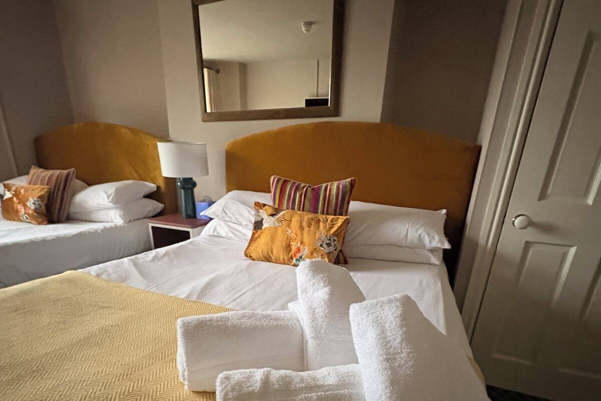 A hotel room with a bed, two nightstands, a mirror, and a door.