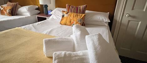 A hotel room with a bed, two nightstands, a mirror, and a door.