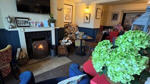 A cozy living room with a fireplace, comfortable seating, a flat-screen TV, and a dining area with a table and chairs. - The Swan Inn (Moreton-in-Marsh)