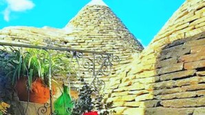 A table with breakfast items, a vase with flowers, and a view of stone walls and a dome structure.