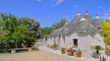 A stone building with conical roofs, surrounded by potted plants and trees.