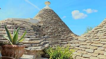A stone structure with a conical roof, surrounded by potted plants.
