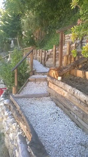 Una escalera de piedra con barandillas de madera que sube a un jardín.
