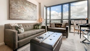 A modern living room with two sofas, a coffee table, and a large abstract painting on the wall. - Bluebird Suites in Pentagon City (Arlington)