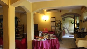 A cozy room with a dining table covered in books and papers, a red sofa, and a staircase leading to another level. - Locanda Strada Della Marina (Senigallia)