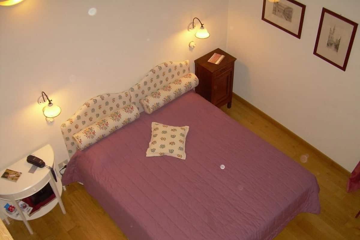 A bedroom with a bed, a nightstand, a lamp, and a small table.